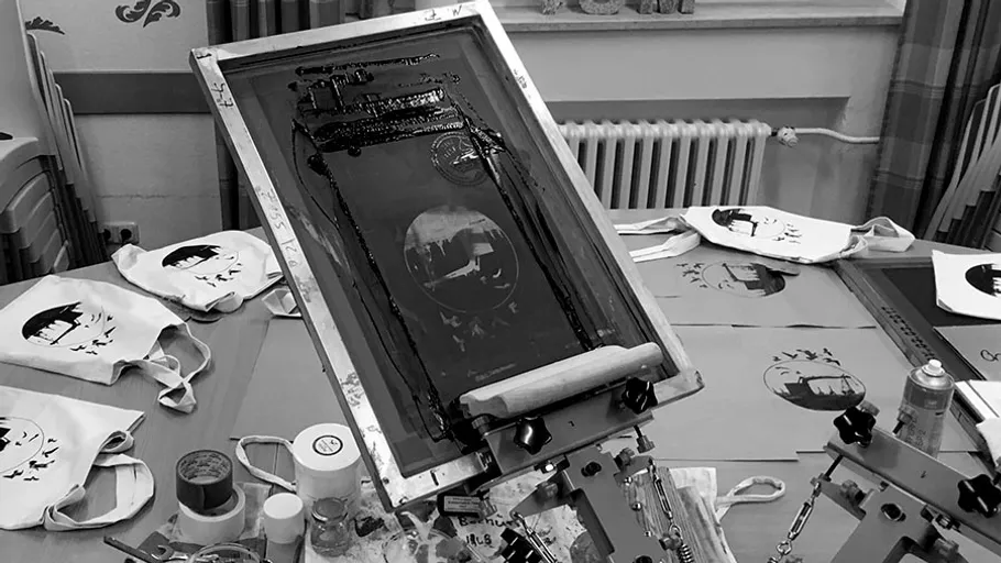 Siebdruckmaschine druckt Motive auf Stofftaschen. Arbeitsumgebung.