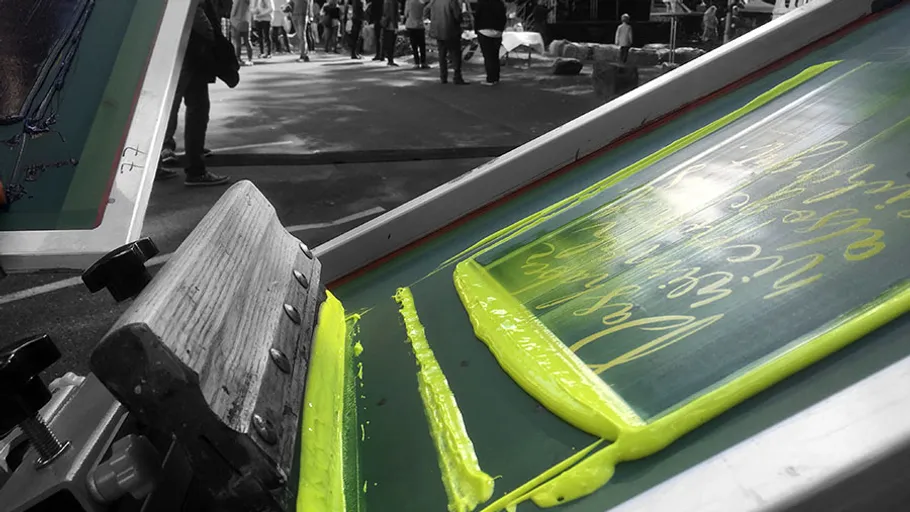 Screen printing machine with yellow color in a busy environment.
