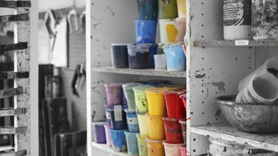 Colorful paint containers on a messy shelf.