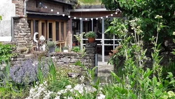 Grüner Garten mit Blumen, Glühbirnen und einer Statue.