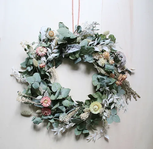 Wreath of dried flowers hangs on a wall.