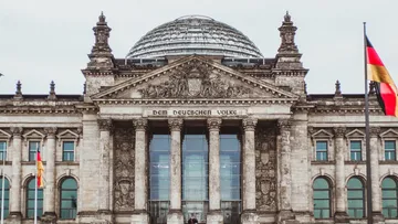 Reichstag building, stands majestically, surrounded by flags.