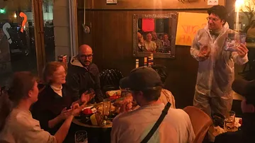 Gruppengespräch in einem Restaurant; jemand präsentiert ein Glas.