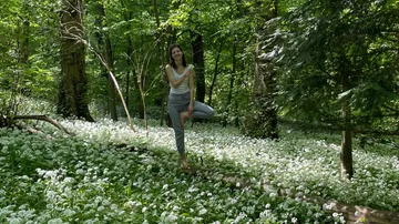 Woman standing on a log in a forest.