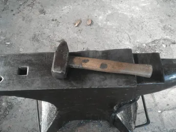 Hammer liegt auf einem Amboss in einer Werkstatt.