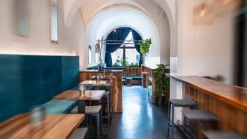 Holztische stehen leer, während Pflanzen im Restaurant stehen.