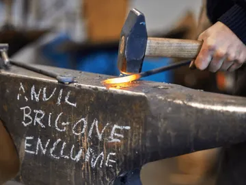 A blacksmith hits a glowing piece of metal.