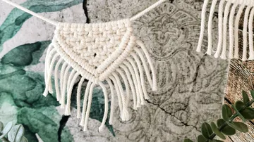 Macramé-Dekoration hängt, umgibt eine grüne Wandgestaltung.