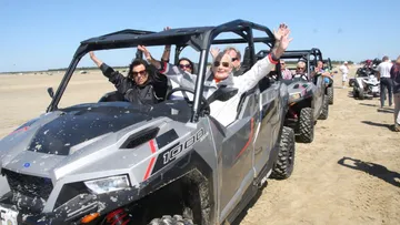 Pipes in the sand, people driving off-road vehicles, sunny beach.
