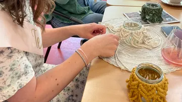 Hands tie yarn around glasses to make decorations.