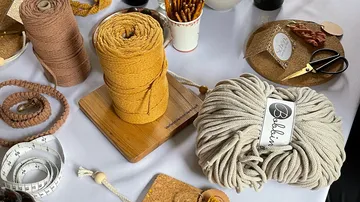 Spools of thread lie on a table with craft materials.