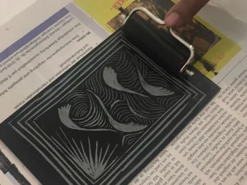 Ein Farbroller gleitet über eine bedruckte Oberfläche.