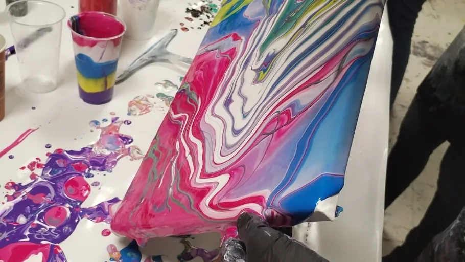 Colourful layers of paint are mixed and moved on a canvas.
