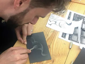 Man draws concentratingly on a black plate.