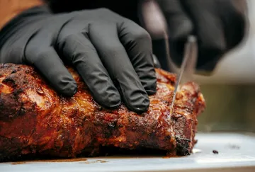 Ein Hand schneidet ein saftiges Stück Fleisch.