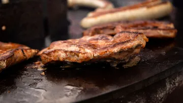 Gegrilltes Fleisch liegt auf einer heißen Grillfläche.