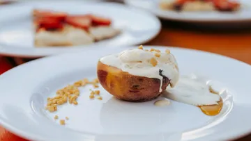 Gegrillte Pfirsichhälfte mit Eiscreme auf weißem Teller.
