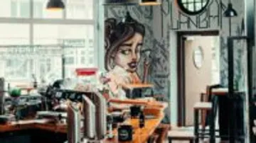 Café with art wall, bar full of drinks, relaxed atmosphere.