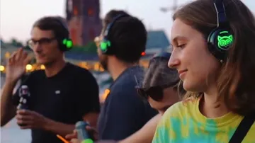 Menschen tragen Kopfhörer, genießen Musik bei Sonnenuntergang.