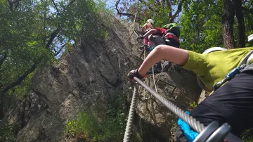 Climbers pull themselves up a rocky slope on ropes.