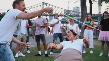 Menschen feiern draußen, tanzen und genießen Musik bei Sonnenuntergang.