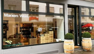 Weinladen mit Glasfenstern, zeigt Weinflaschen und Kisten.