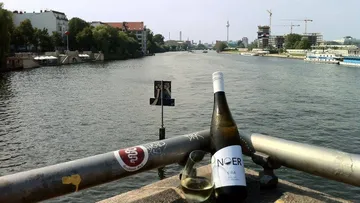 There is white wine on a railing on the riverbank.