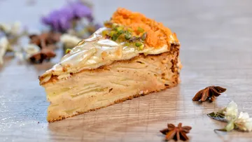 Kuchenstück liegt auf einer Holzoberfläche, umgeben von Gewürzen.
