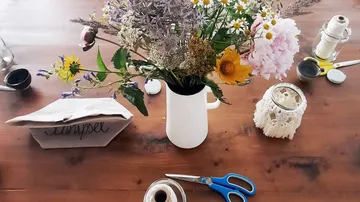 Blumenstrauß in einer weißen Vase auf einem Holztisch.