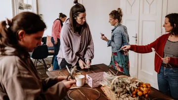 Frauen arbeiten an einem Tisch mit Bastelmaterialien.