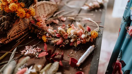 Blumenkranz liegt neben getrockneten Blumen auf Tisch.