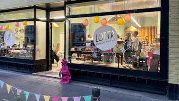 Shop window with colorful decorations and happy customers.