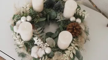Wreath with candles, decorated with natural materials, on table.
