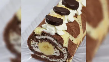 Schokoladen-Bananenrolle liegt auf einem weißen Teller.