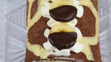 Schokoladenkuchen mit Bananen und Sahne auf einem Teller.