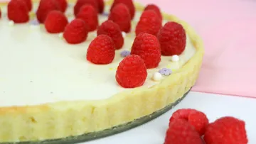 Cheesecake with fresh raspberries on a white plate.