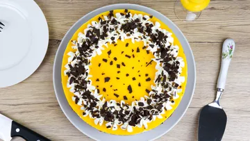 Yellow cake with cream and chocolate on a plate.