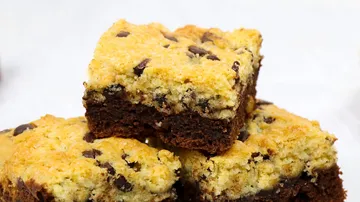 Chocolate chip cookies are layered on top of each other on a bright background.