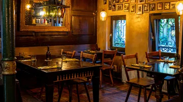 Dark wooden table, chairs, cozy restaurant with pictures.
