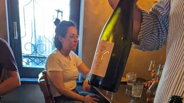 A person holds a wine bottle in a restaurant.