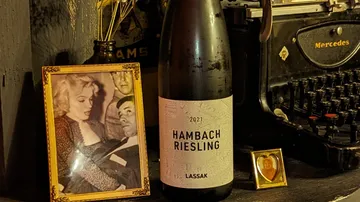 Flasche Riesling steht neben Bilderrahmen und Schreibmaschine.