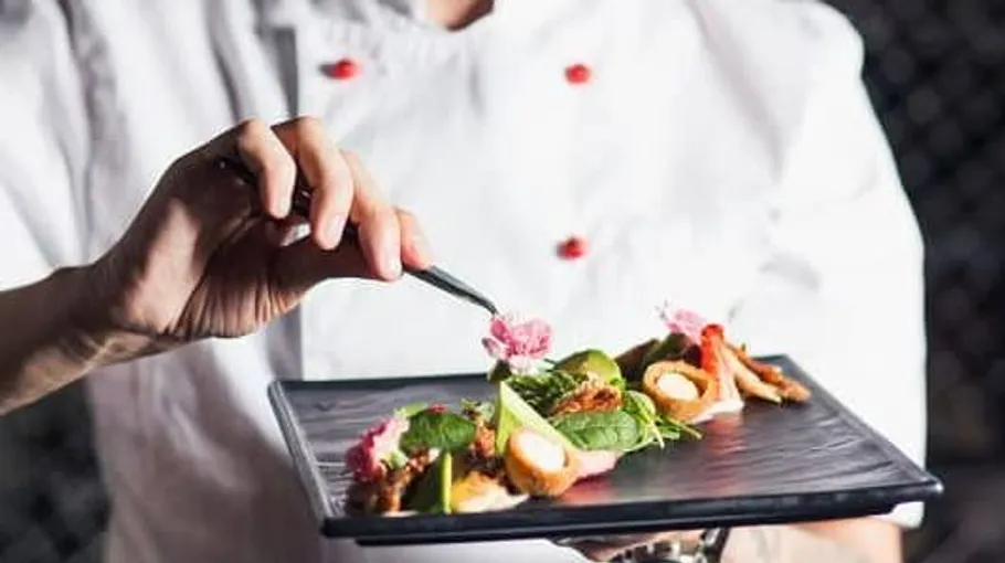 A chef artfully arranges a dish on a plate.
