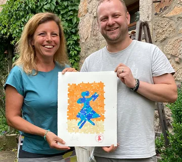 Two people are holding a puzzle with a dancing figure.