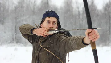 A man aims with a bow in the snow.