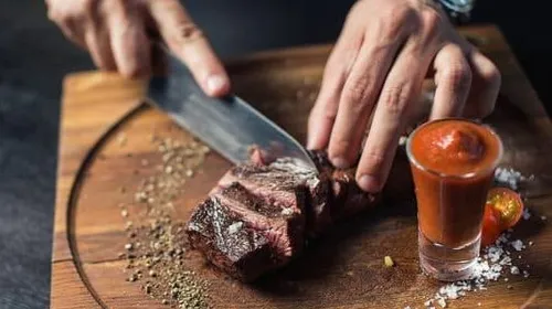 A piece of meat is cut on a wooden board.