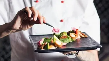 Chef artfully decorates a dish on a plate.