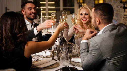 Friends bump into glasses in an elegant restaurant atmosphere.