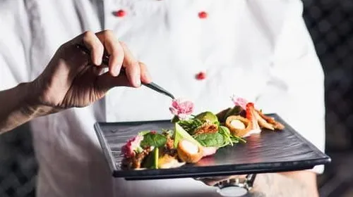 A chef is decorating a plate with delicious food.