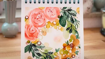 Ein Kalenderblatt zeigt lebhafte Blumenillustrationen auf Tisch.