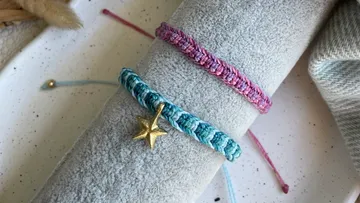 Bunte Armbänder liegen auf einem grauen Tuch.